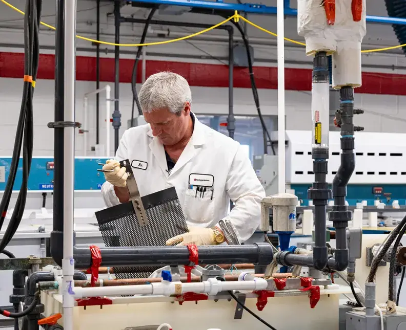 MacDermid Enthone facility employee handling a freshly treated part